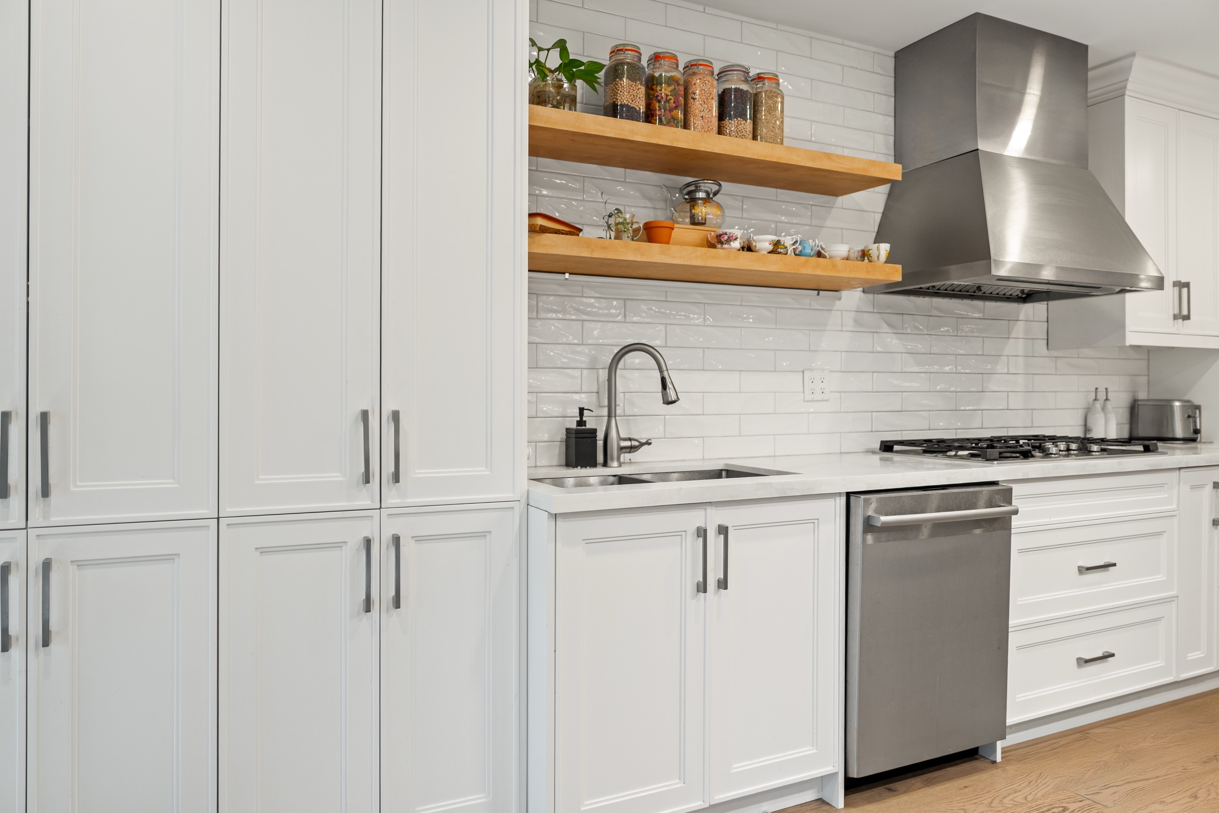 Straight metal handles on white framed cabinet doors