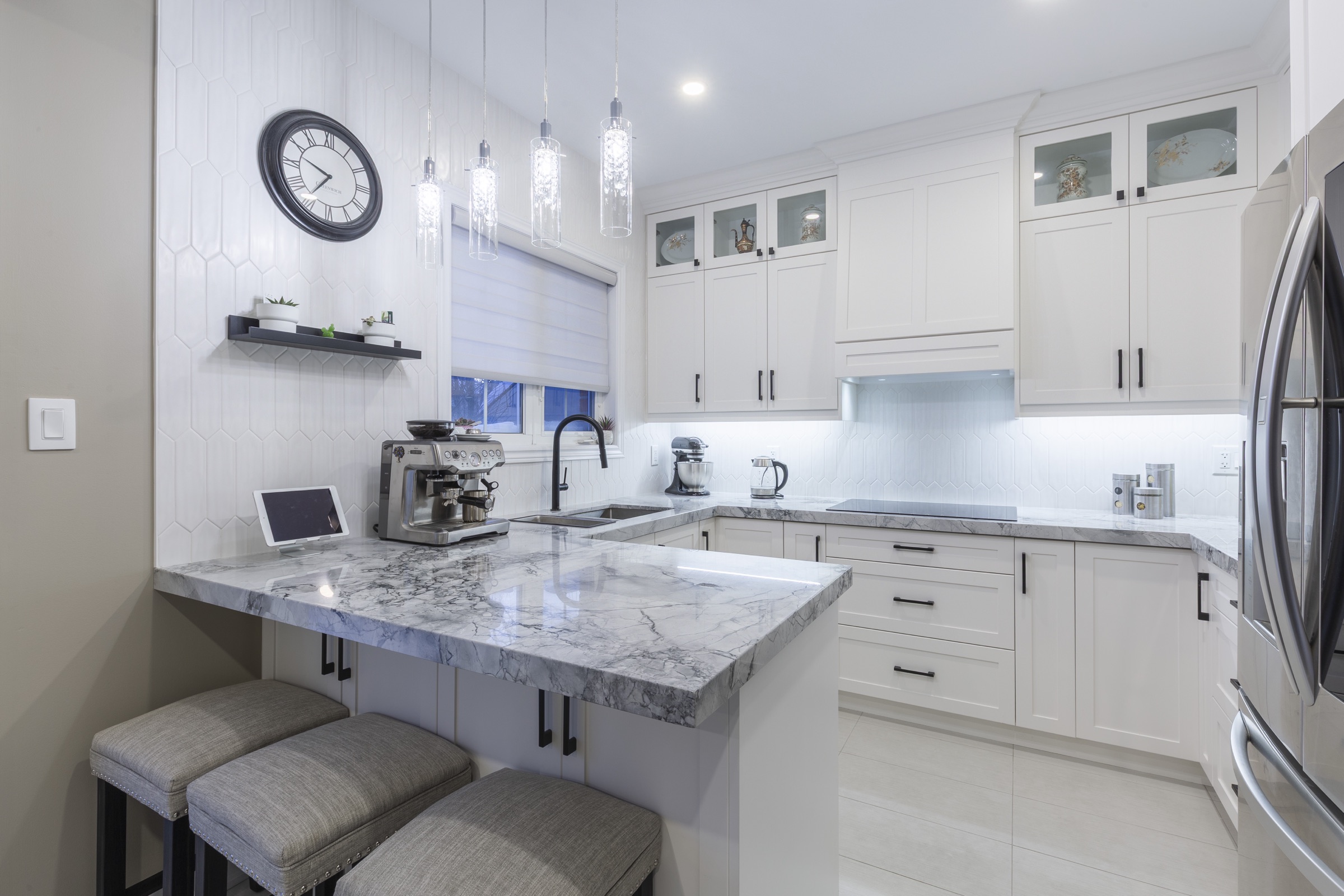 White kitchen with a veined countertop and two stools