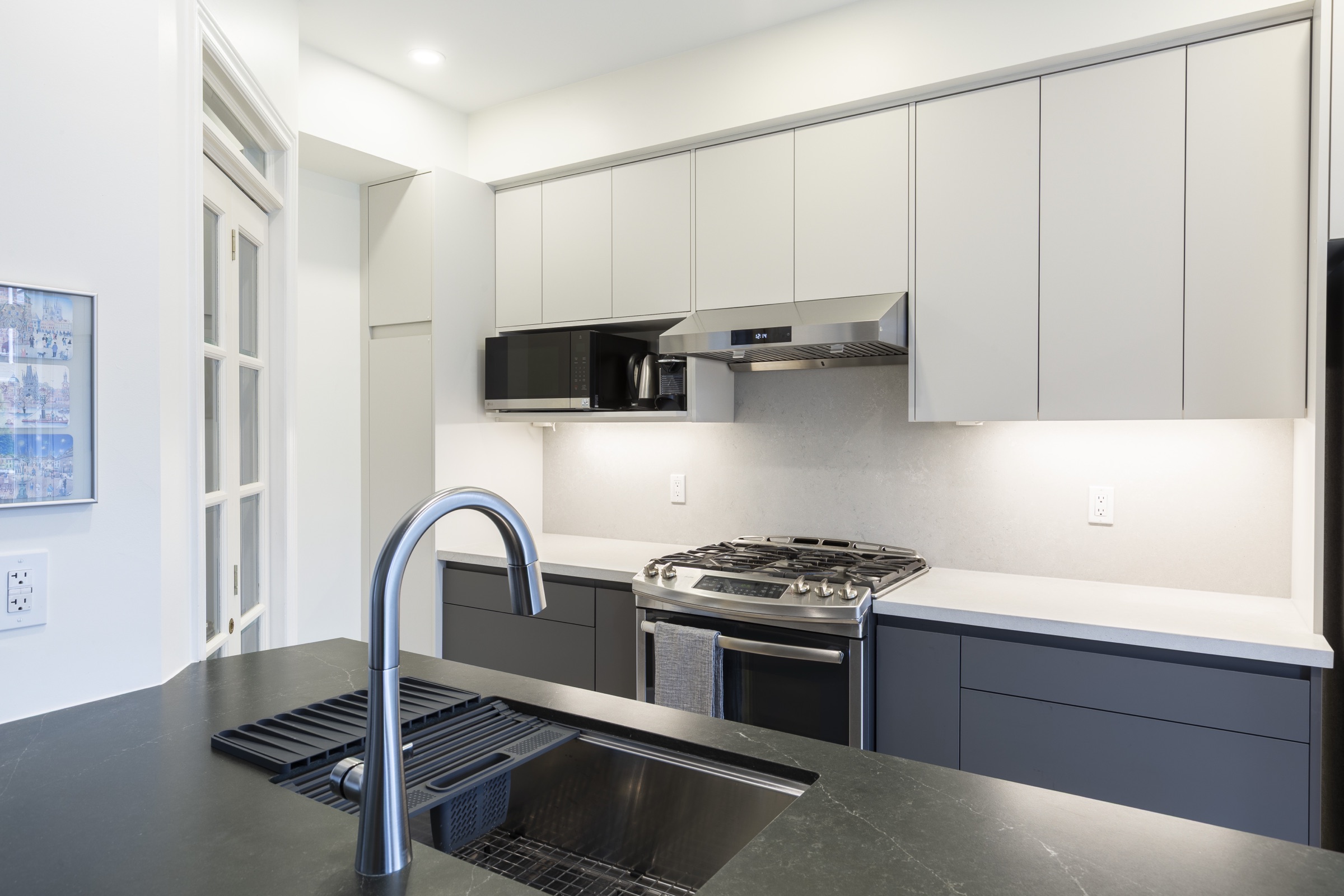Kitchen with light upper cabinets, dark lower cabinets and a dark island surface