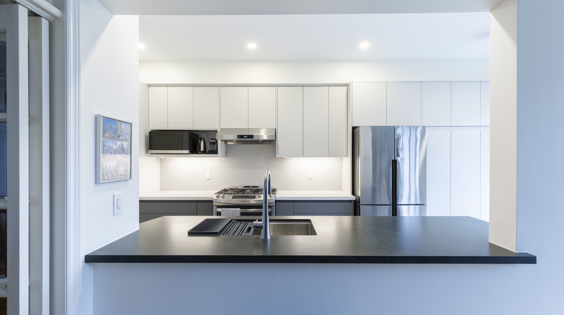Kitchen with light upper cabinets, dark lower cabinets and a dark island surface