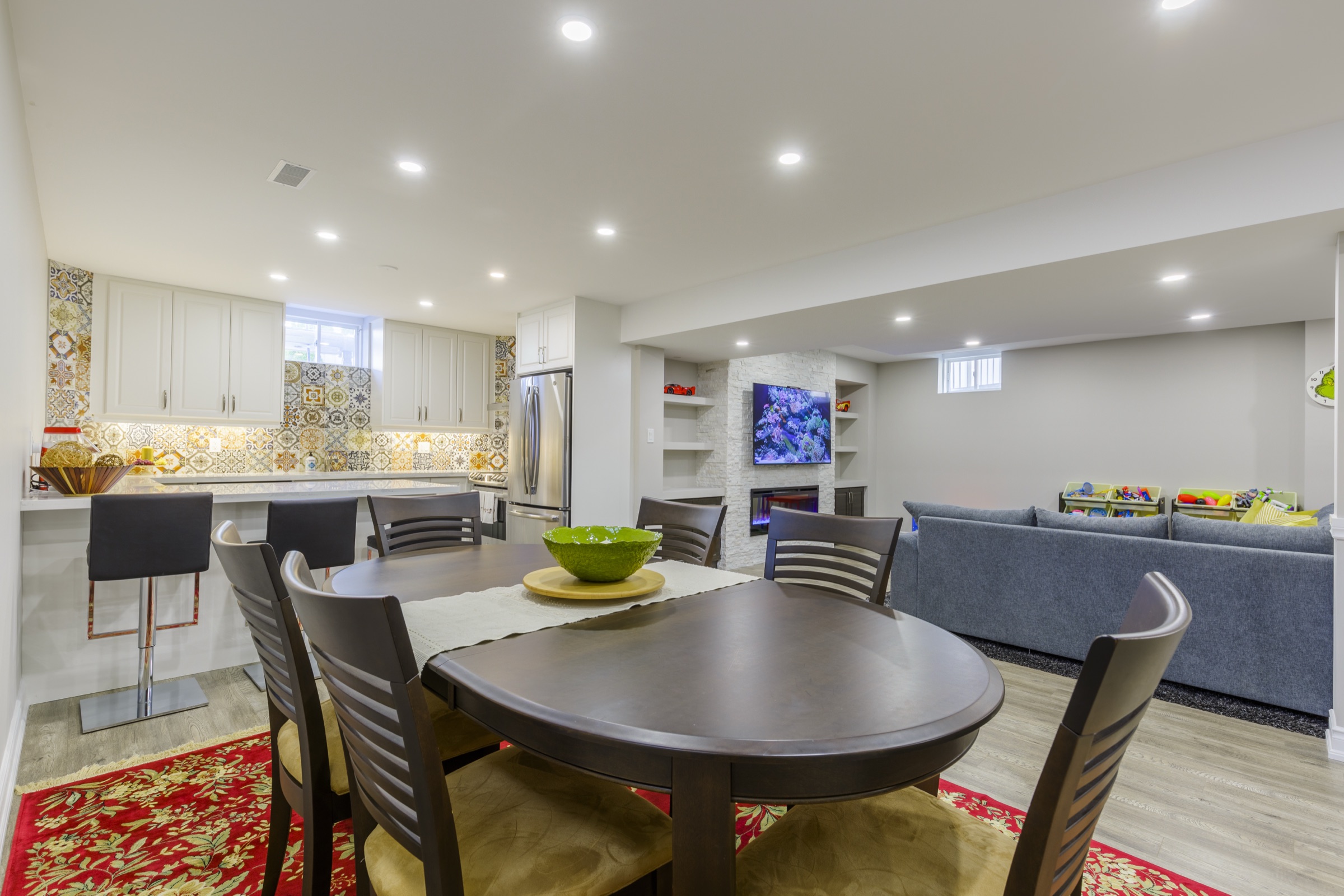Cream kitchen cabinetry with patterned backsplash beside dining table and sofa